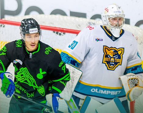 На изображении два хоккеиста стоят у ворот. Игрок в черной форме украшен зелеными элементами, а вратарь—в белой форме с изображением тигра и надписью OLIMPBET. Они сосредоточены на игре